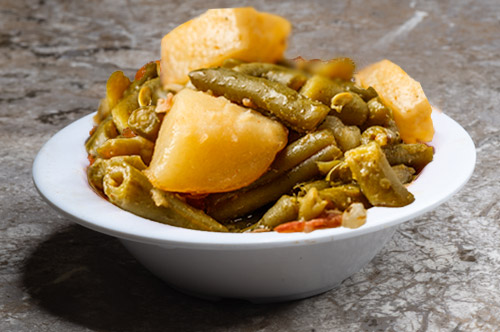 A mouthwatering bowl of green beans, a delightful addition to our authentic soul food menu, showcasing tender and flavorful green beans cooked to perfection.